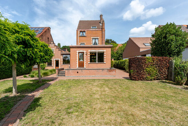 Deze karaktervolle burgerwoning in Vlaamse neotraditionele stijl, met haar statige trapgevel en authentieke elementen, ligt op een royaal perceel van 860 m² in het landelijke Beigem (Grimbergen).

Op het gelijkvloers bevindt zich de inkomhal die toegang 