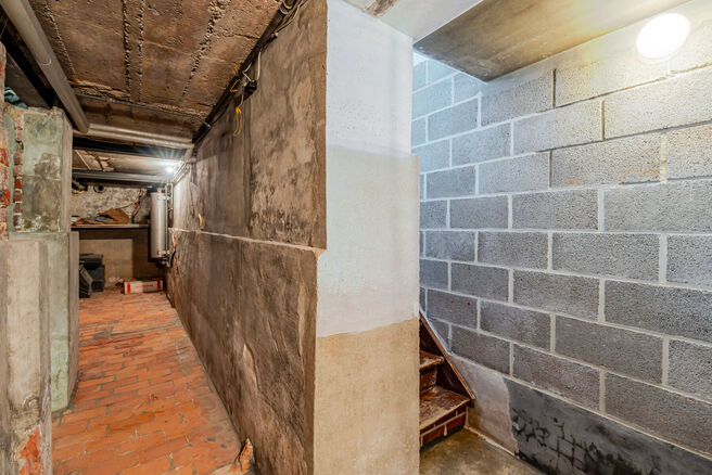 Deze karaktervolle burgerwoning in Vlaamse neotraditionele stijl, met haar statige trapgevel en authentieke elementen, ligt op een royaal perceel van 860 m² in het landelijke Beigem (Grimbergen).

Op het gelijkvloers bevindt zich de inkomhal die toegang 