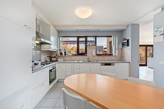 Deze ruime villa met maar liefst 5 slaapkamers en 3 badkamers is gelegen in een residenti&euml;le woonwijk, op een perceel van 15a85ca.

Bij het betreden van de woning komt men in de inkomhal met apart gastentoilet. In 2002 werd de woning uitgebreid met een a