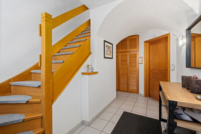 Deze ruime villa met maar liefst 5 slaapkamers en 3 badkamers is gelegen in een residenti&euml;le woonwijk, op een perceel van 15a85ca.

Bij het betreden van de woning komt men in de inkomhal met apart gastentoilet. In 2002 werd de woning uitgebreid met een a