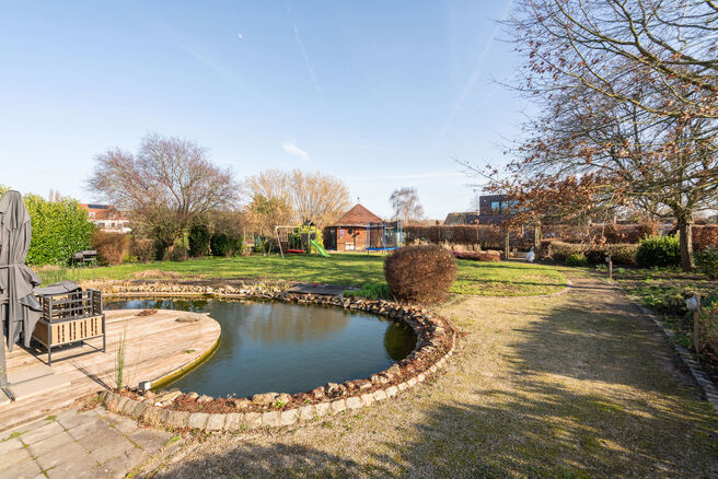 Deze ruime villa met maar liefst 5 slaapkamers en 3 badkamers is gelegen in een residenti&euml;le woonwijk, op een perceel van 15a85ca.

Bij het betreden van de woning komt men in de inkomhal met apart gastentoilet. In 2002 werd de woning uitgebreid met een a