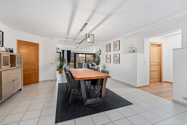 Deze ruime villa met maar liefst 5 slaapkamers en 3 badkamers is gelegen in een residenti&euml;le woonwijk, op een perceel van 15a85ca.

Bij het betreden van de woning komt men in de inkomhal met apart gastentoilet. In 2002 werd de woning uitgebreid met een a