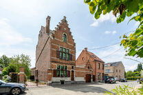 Deze karaktervolle burgerwoning in Vlaamse neotraditionele stijl, met haar statige trapgevel en authentieke elementen, ligt op een royaal perceel van 860 m² in het landelijke Beigem (Grimbergen).

Op het gelijkvloers bevindt zich de inkomhal die toegang 