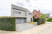 Deze prachtige, moderne gezinswoning met 4 slaapkamers, 2 badkamers, garage, dubbele autostaanplaats en tuin is uitstekend gelegen in een rustige, landelijke en autoluwe woonwijk.
De woning combineert een hedendaagse architectuur met royale leefruimtes, v